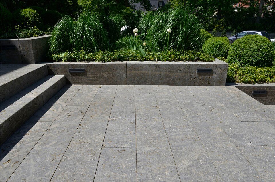 Natursteinmauern als Eingrenzung von Beeten am Rande einer Terrasse